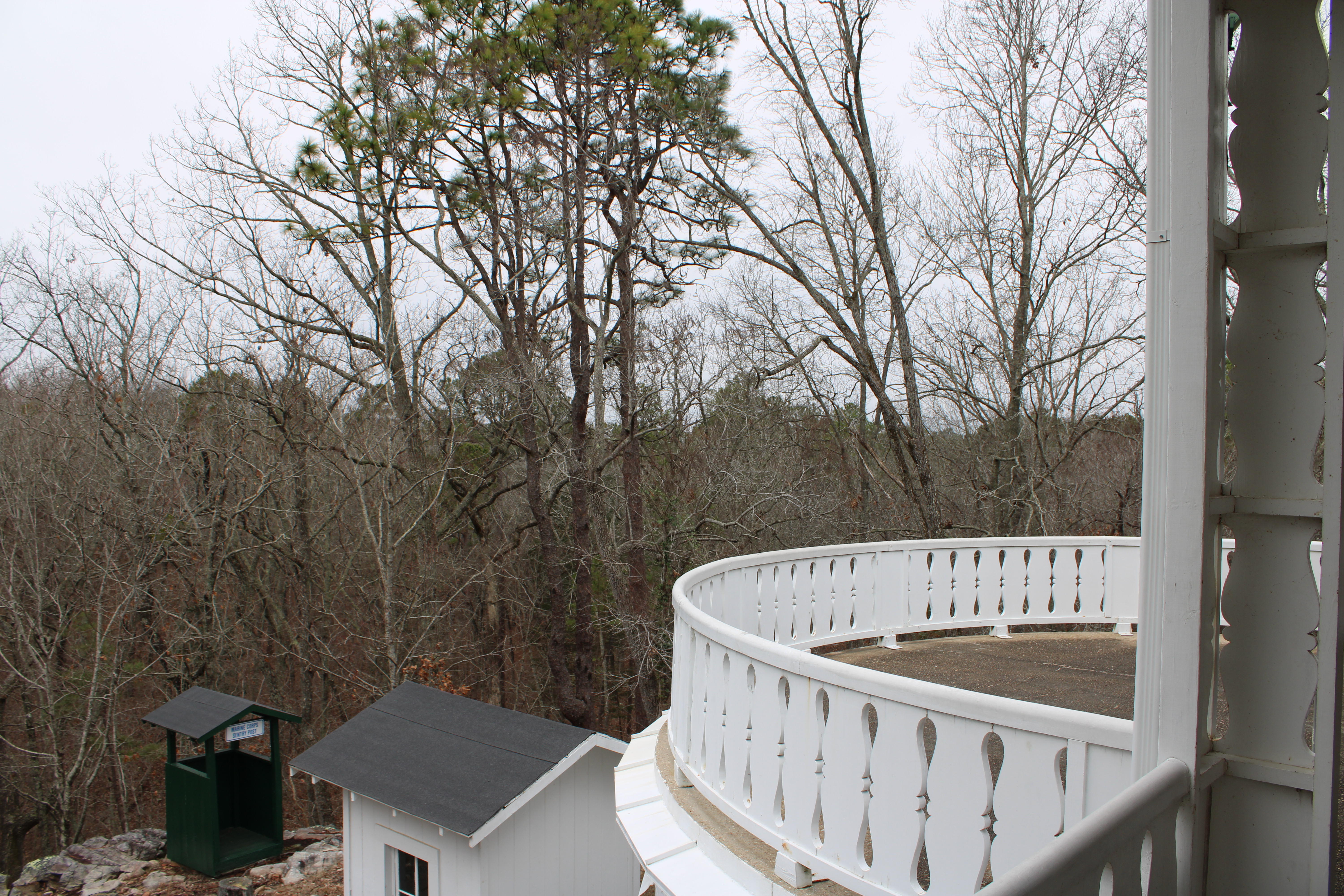 The back porch of the main cottage, with a circular high up design that FDR thought of as resembling the deck of a ship. The view from the deck is of the forest surrounding the property.